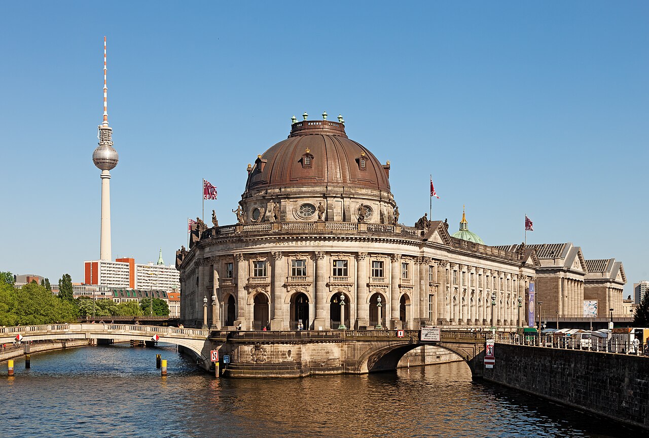 The Bode-Museum on Museum Island in Berlin: a domed neo-baroque building standing on the point where the Spree divides, with bridges over the water in front of it and the television tower rising behind to the left