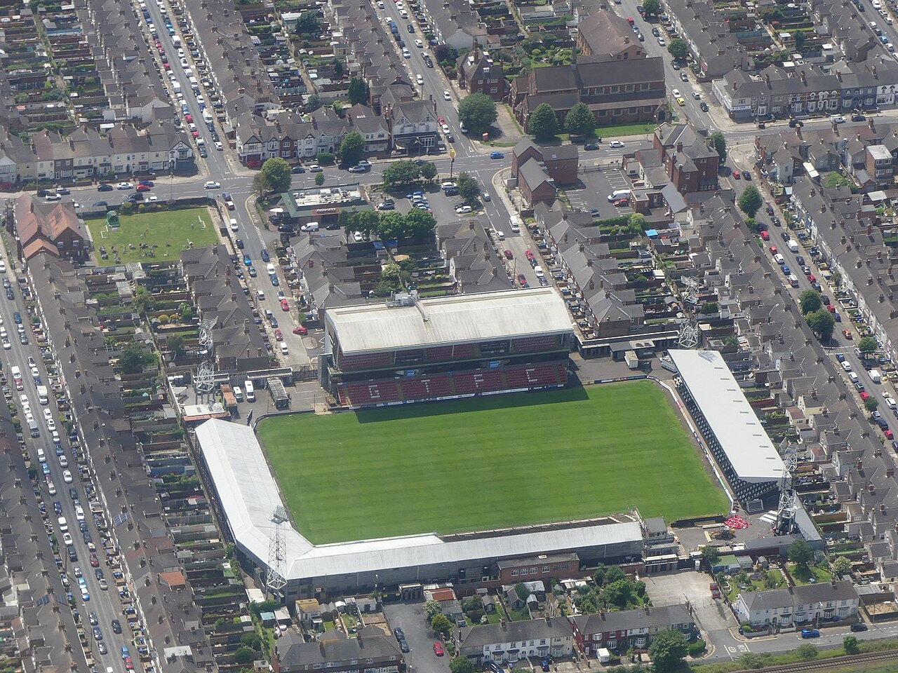 Blundell Park from the air: a small four-sided football ground with GTFC picked out in the seats of one stand, wedged tightly among rows of terraced houses, allotments and a main road, on completely flat ground near the coast