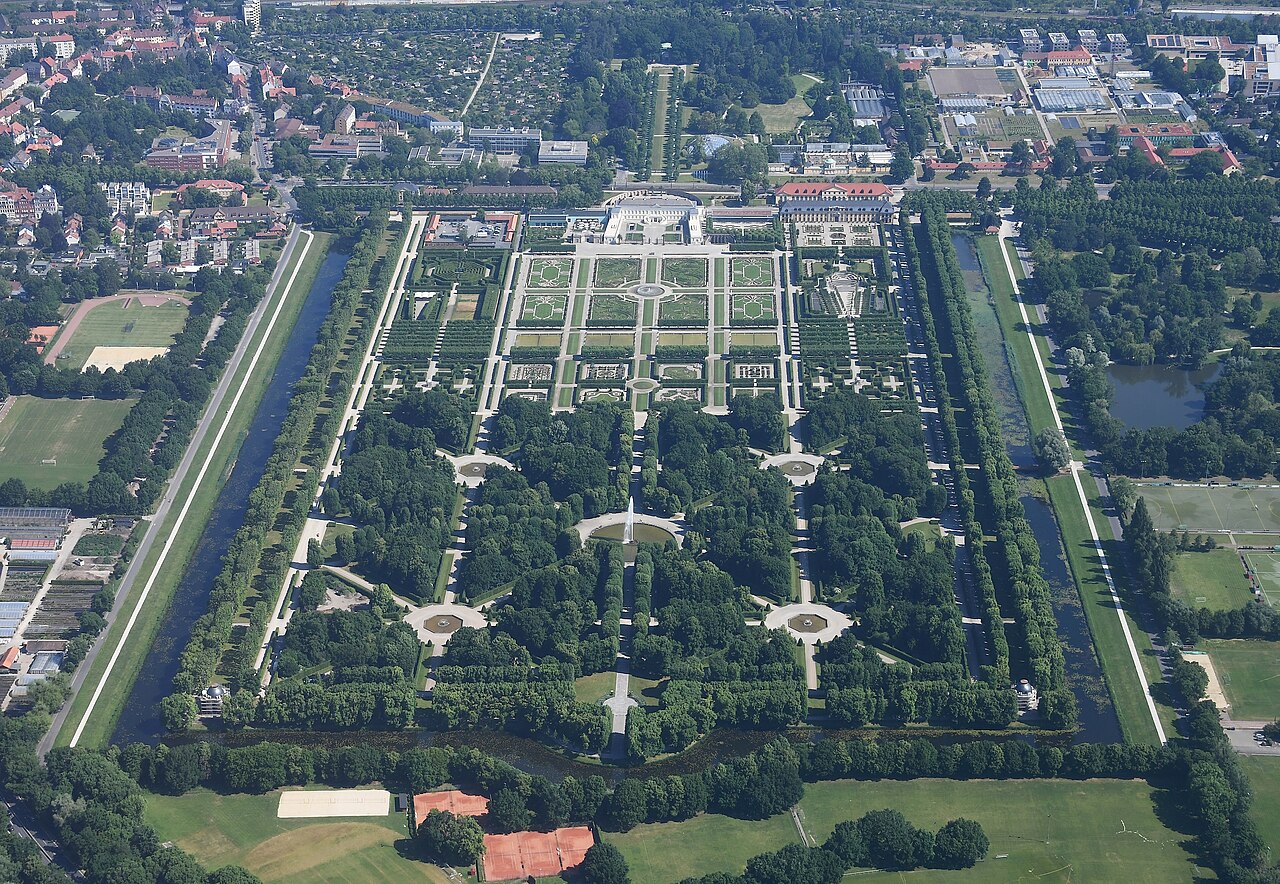The Great Garden at Herrenhausen from the air: a vast rectangular baroque garden with symmetrical parterres of clipped hedges and flower beds, avenues of trees, a fountain on the central axis and straight water channels running down both long sides