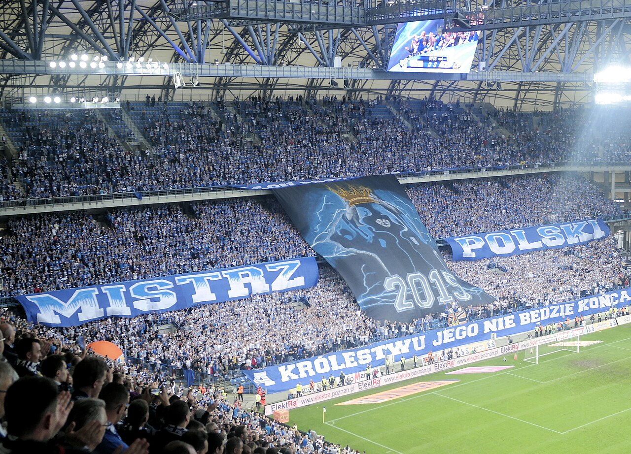 The interior of the Poznań stadium packed with supporters in blue and white, a vast banner reading MISTRZ POLSKI 2015 stretched across the stand behind the goal