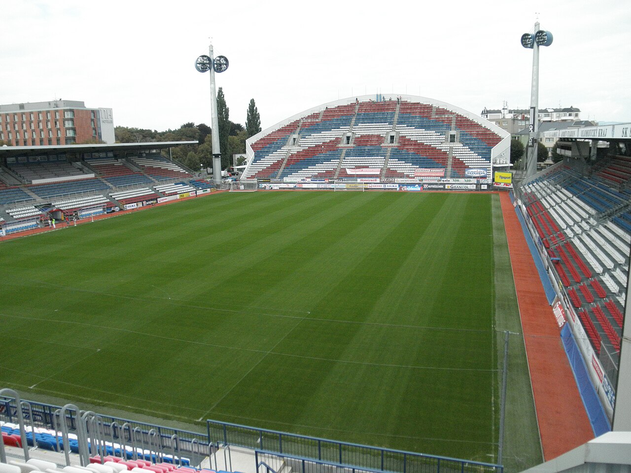The Andrův stadion in Olomouc seen from a corner: stands in red, white and blue, one with a curved arched roof, the pitch running right up to the seats with no running track